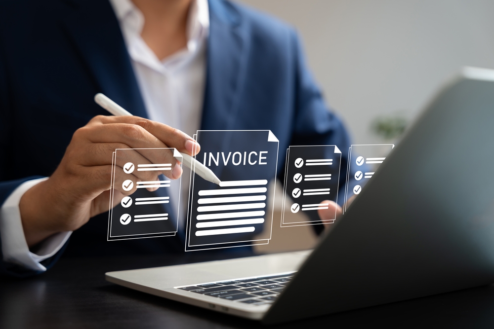 Business owner reviewing invoices and financial documents on a laptop